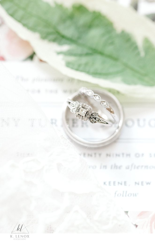 Antique White gold diamond engagement ring with delicate white gold wedding band photographed on a simple white wedding invitation.