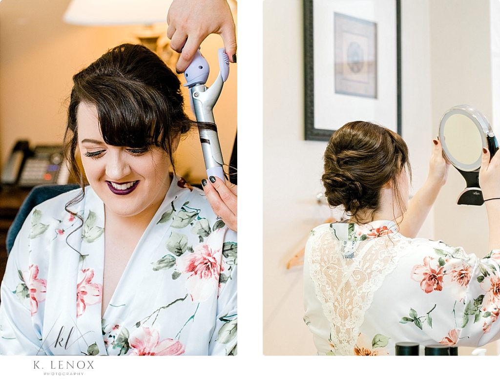 Bride wearing floral robe gets her hair done on her wedding day. 