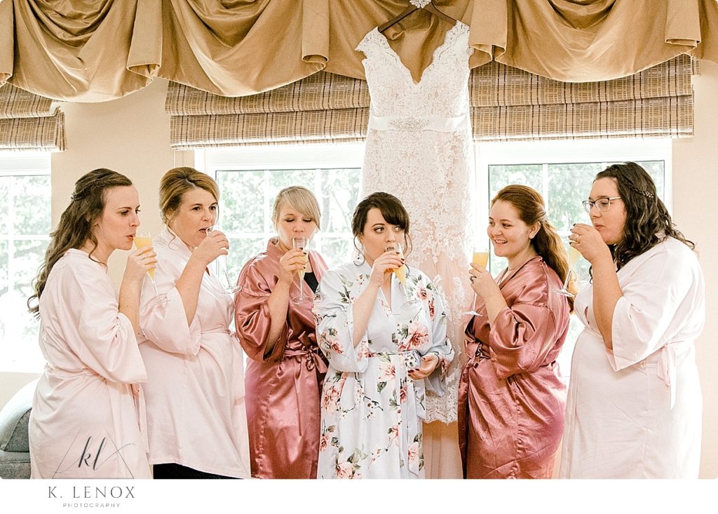 Bride and her bridesmaids take a toast of champagne while they are getting ready. 