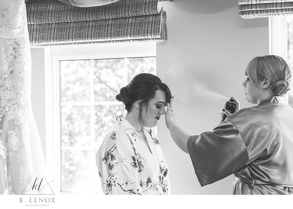 Black and white photo of a bride getting her hair sprayed by the hair stylist on her wedding day. 