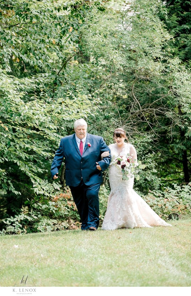 A bride is escorted by her father on the wedding day at Stonewall Farm. 