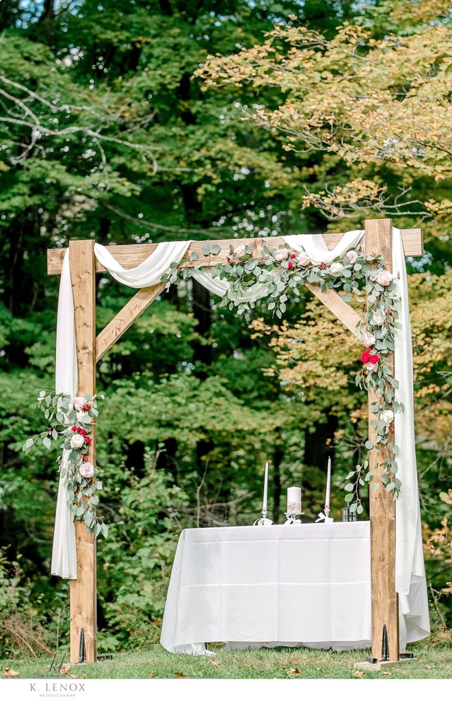 Homemade wooden arbor decorated with drapery and flowers for a wedding ceremony at Stonewall Farm. 