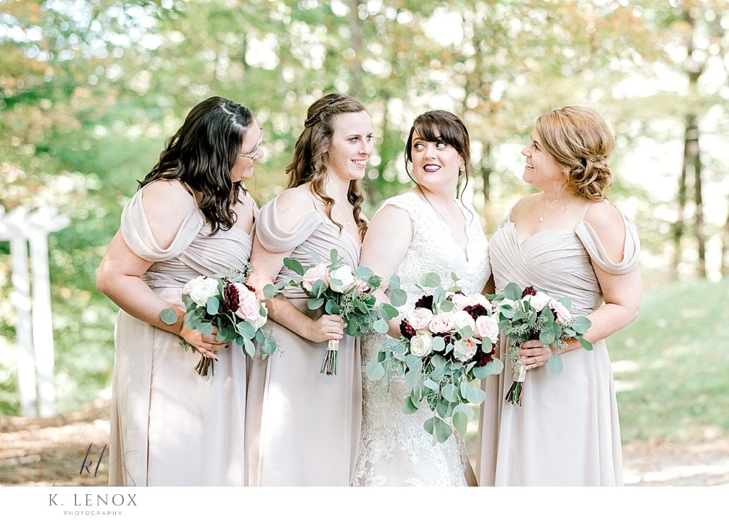One bride and three bridesmaids are standing together holding their floral bouquets at Stonewall Farm 