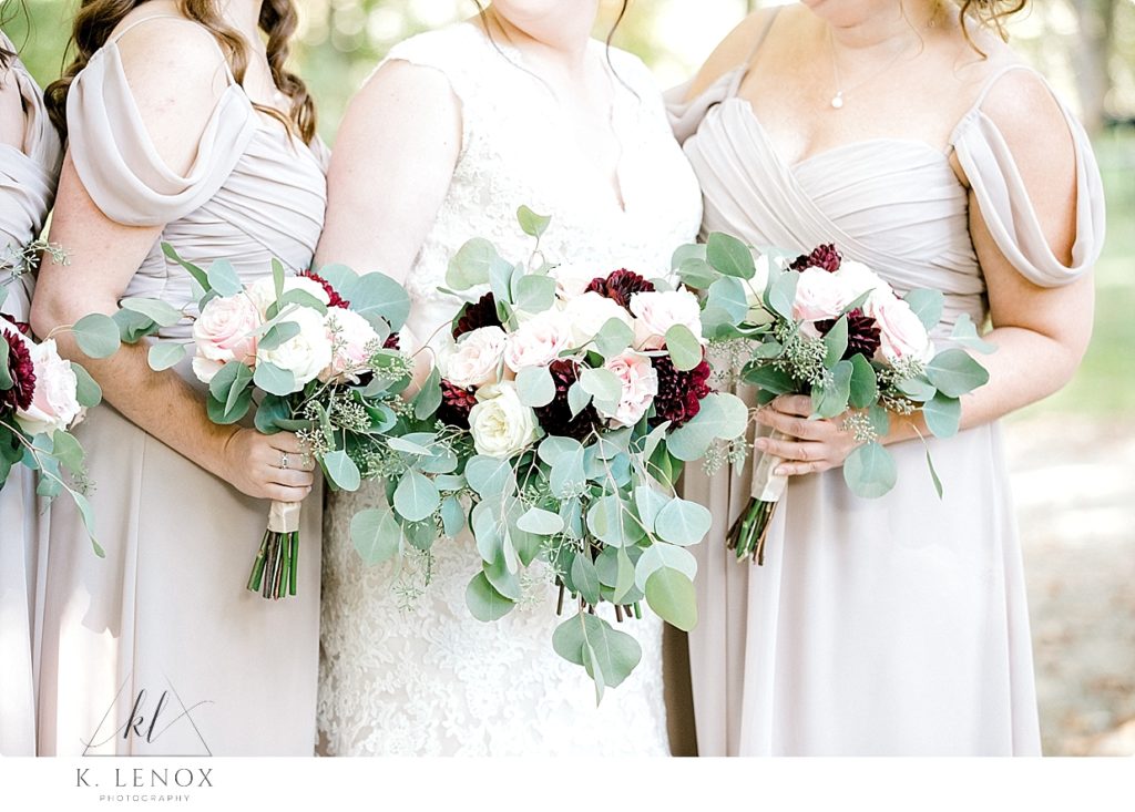 Bridesmaids and Bride holding floral bouquets with white and pink roses mixed with lots of greenery. 