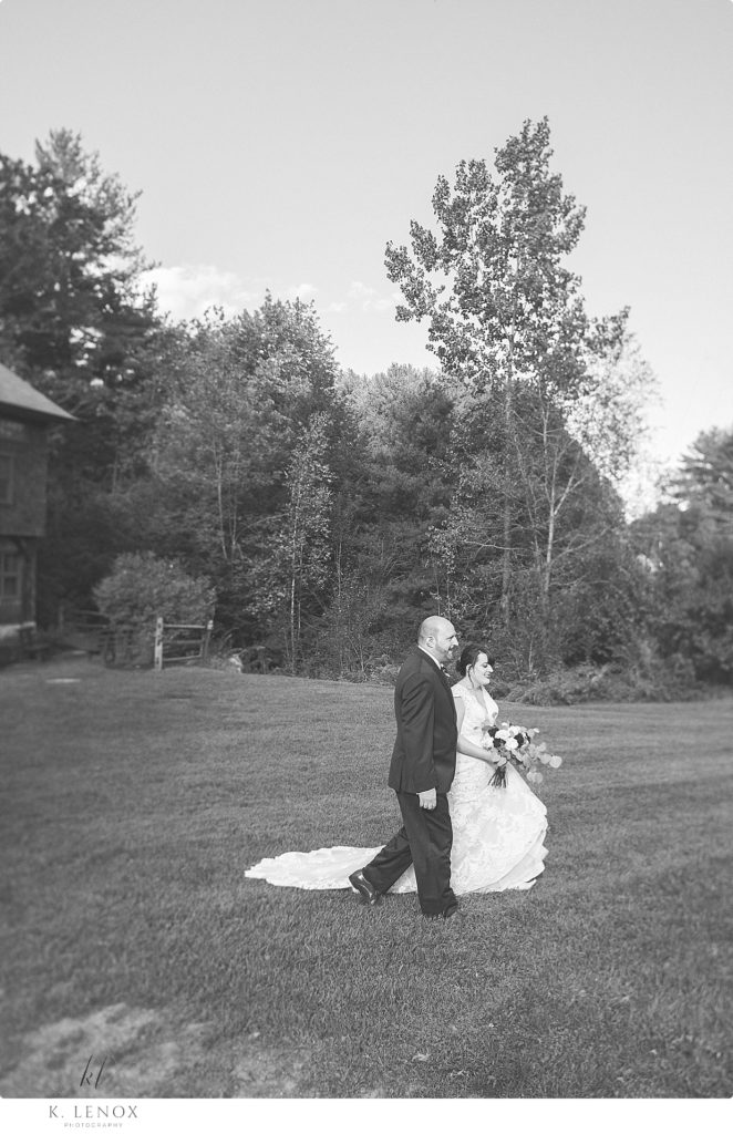 Black and White photo of a bride and groom walking at stonewall farm. 