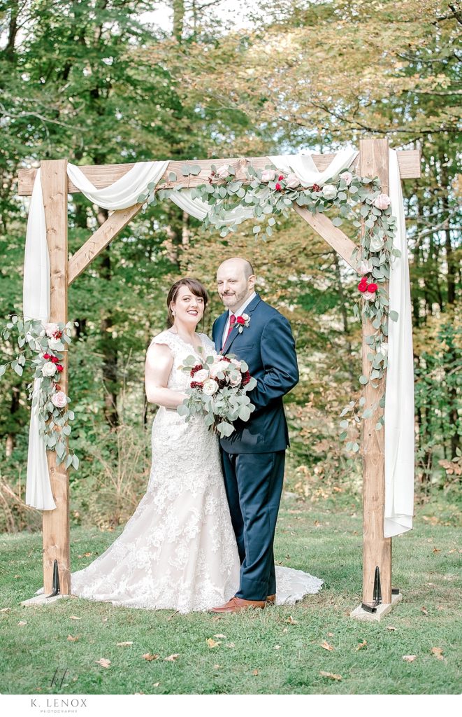 Light and Airy formal portrait of a bride and groom in front of their custom wedding day arch at Stonewall farm