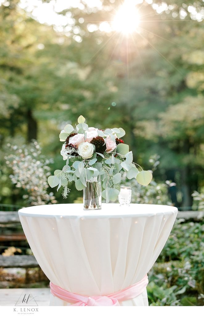 Wedding bouquet sits on a high table as the sun shines down. Taken at Stonewall Farm by K. Lenox Photography