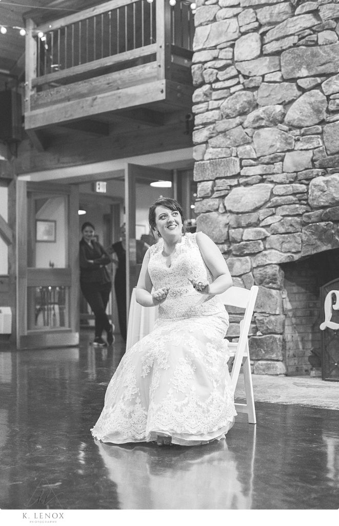 Black and White photo of a bride sitting in a chair at her wedding reception. 