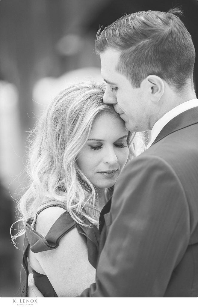 Close up and Candid black and white photo of a man and woman hugging and embracing during their engagement photo session. 