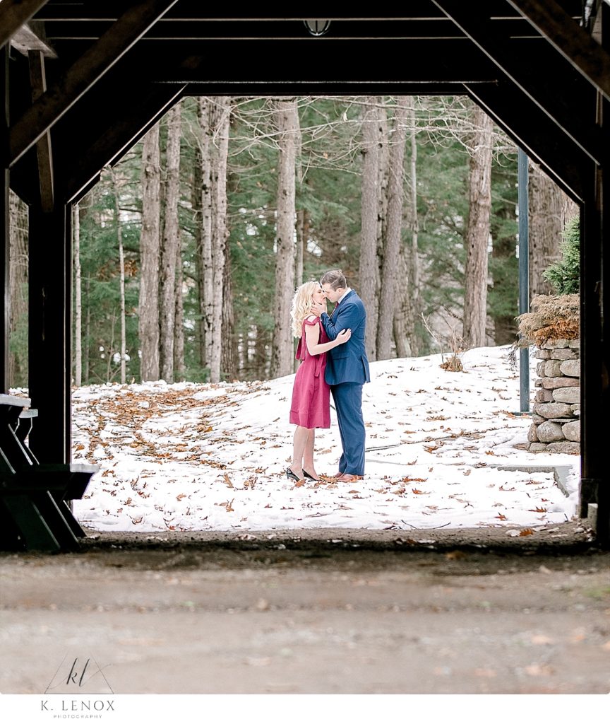 Engaged couple embrace and kiss through the barn at Stonewall farm. 