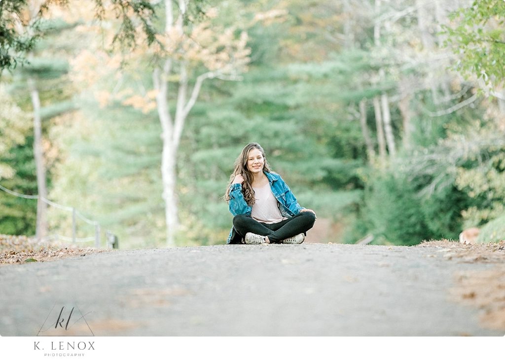 Senior Photo in Chesterfield NH of a girl wearing a Vintage Levi's Jean Jacket sitting on a country road. 