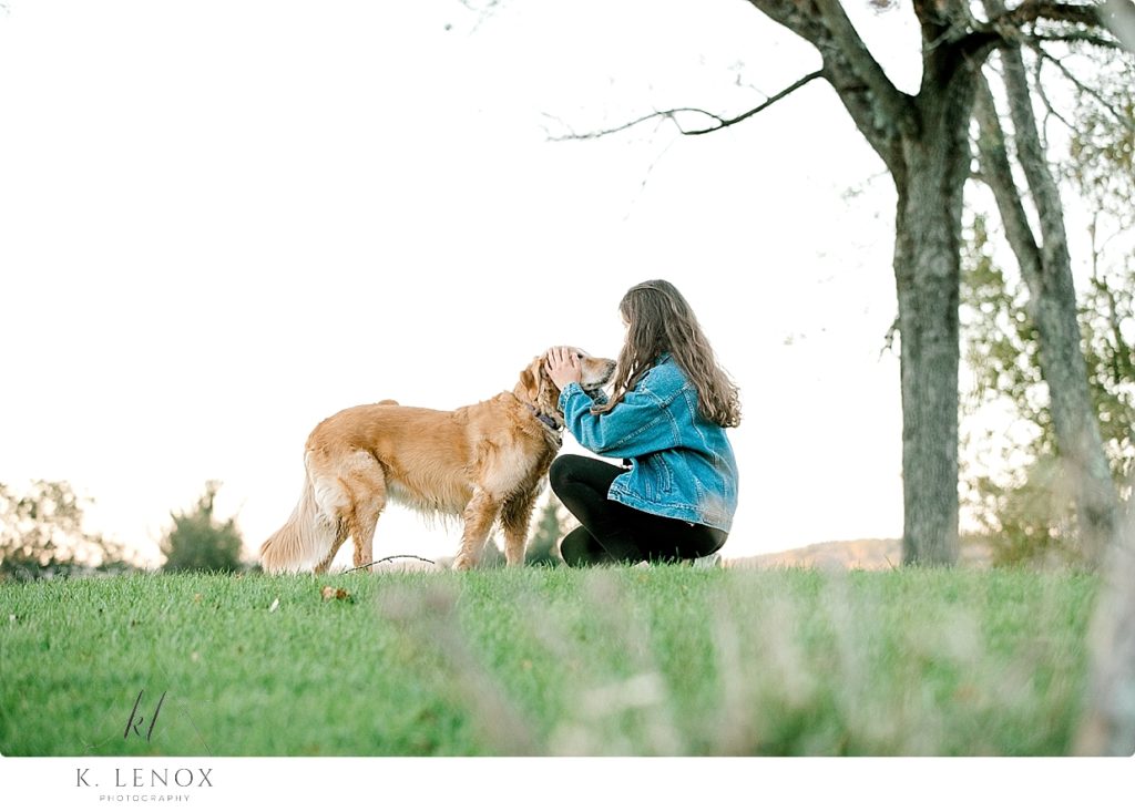 Senior Photo in Chesterfield NH of a girl wearing a Vintage Levi's Jean Jacket playing with her golden retriever