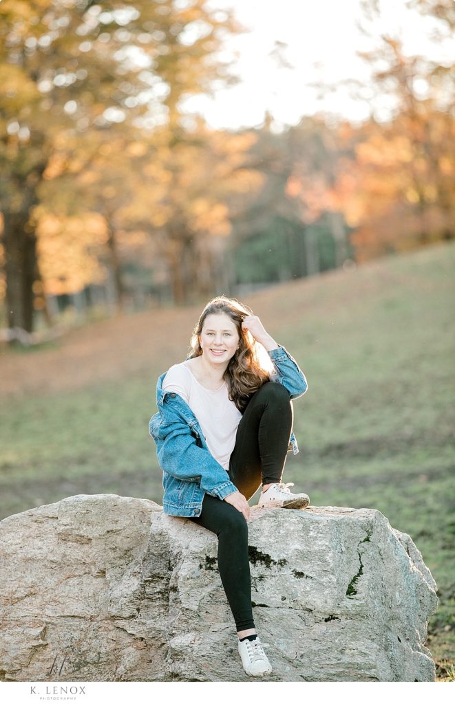 Chesterfield Senior Photos showing a girl wearing a vintage Levi's Jean Jacket sitting on a big rock. 