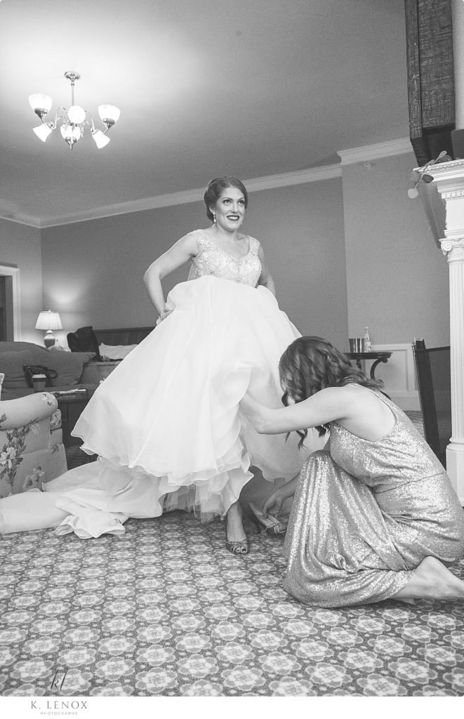 Black and white photo of a bride getting help getting ready in the bridal suite at the Omni Mount Washington Resort. 