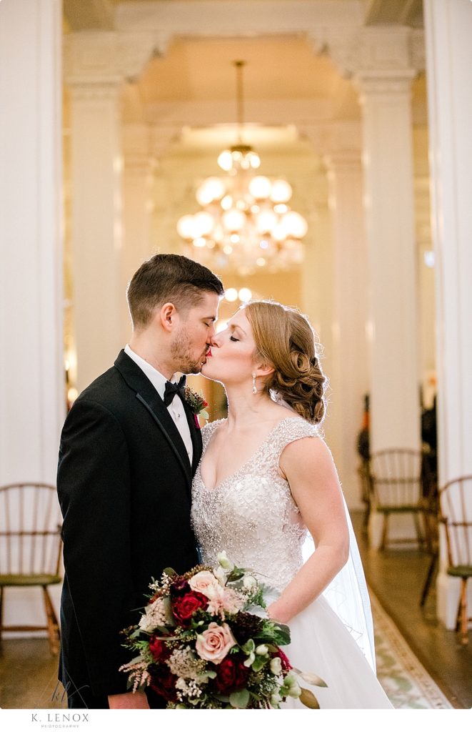 Bride and Groom Kiss in the lobby of the Omni Mount Washington Resort during their Christmas wedding. 
