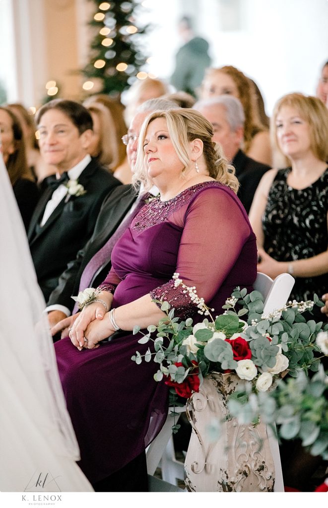 Mother of the Groom wearing a purple dress watches her son get married. 