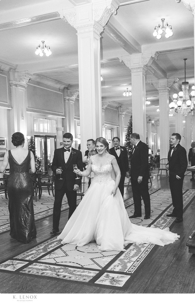 Black and White photo of a bride and groom walking with Champaign as they walk in the lobby of the Omni Mount Washington Resort. 