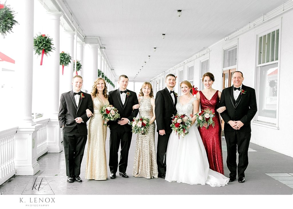 Wedding Party wearing Red and Gold stand with men in Black Tuxedos at the Omni Mount Washington Resort- Christmas Wedding. 