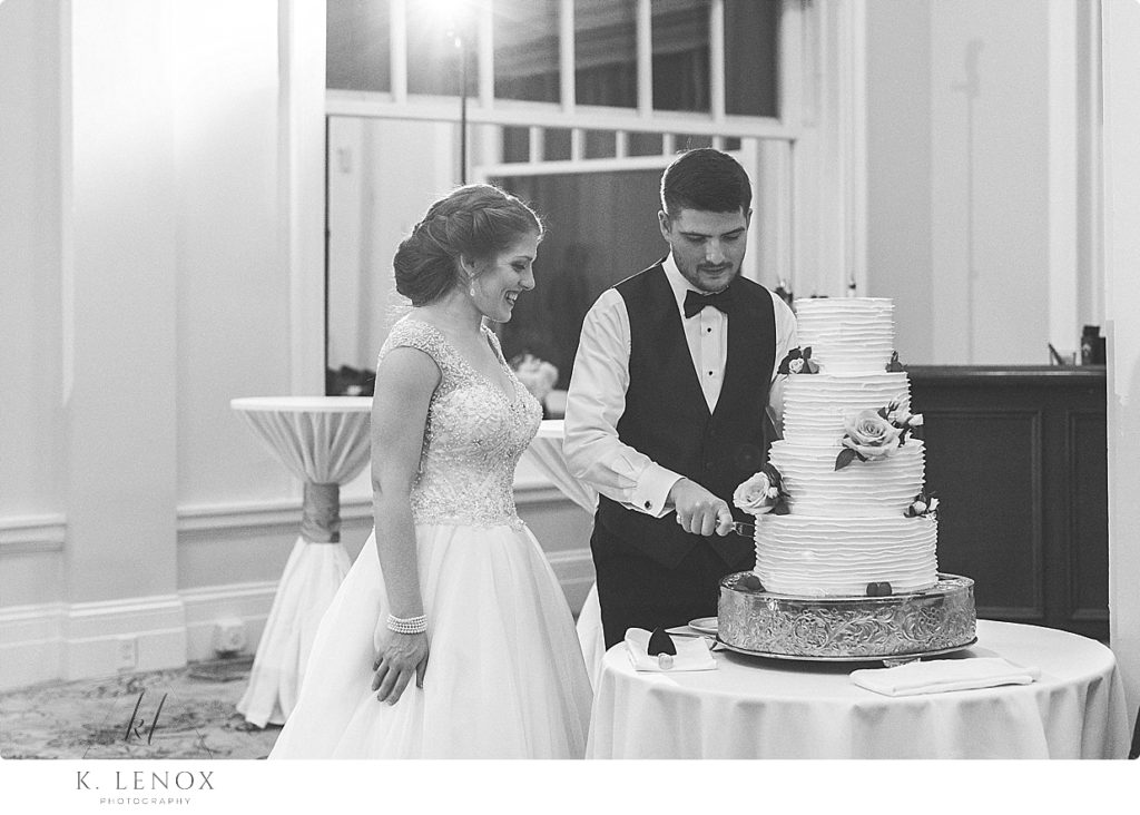 Black and White photo of the bride and groom cutting their wedding cake. 