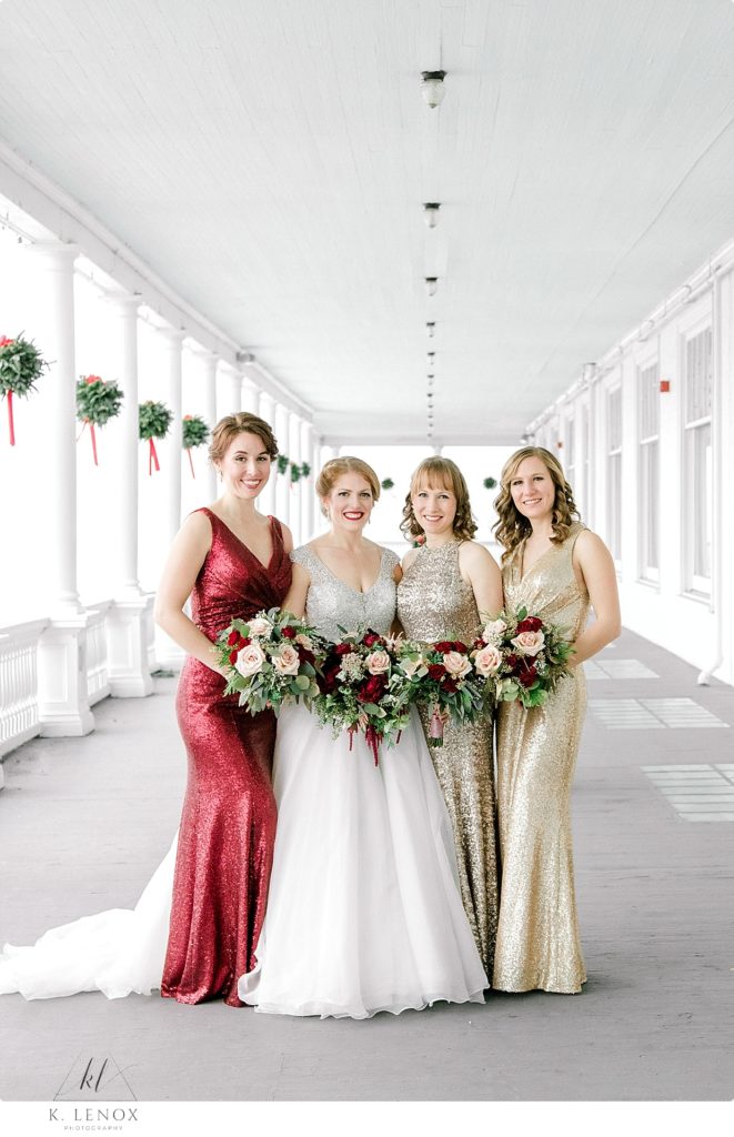 Bridesmaids wearing gold sequin dresses and the Matron of Honor wearing red sequin dresses holding bouquets. 