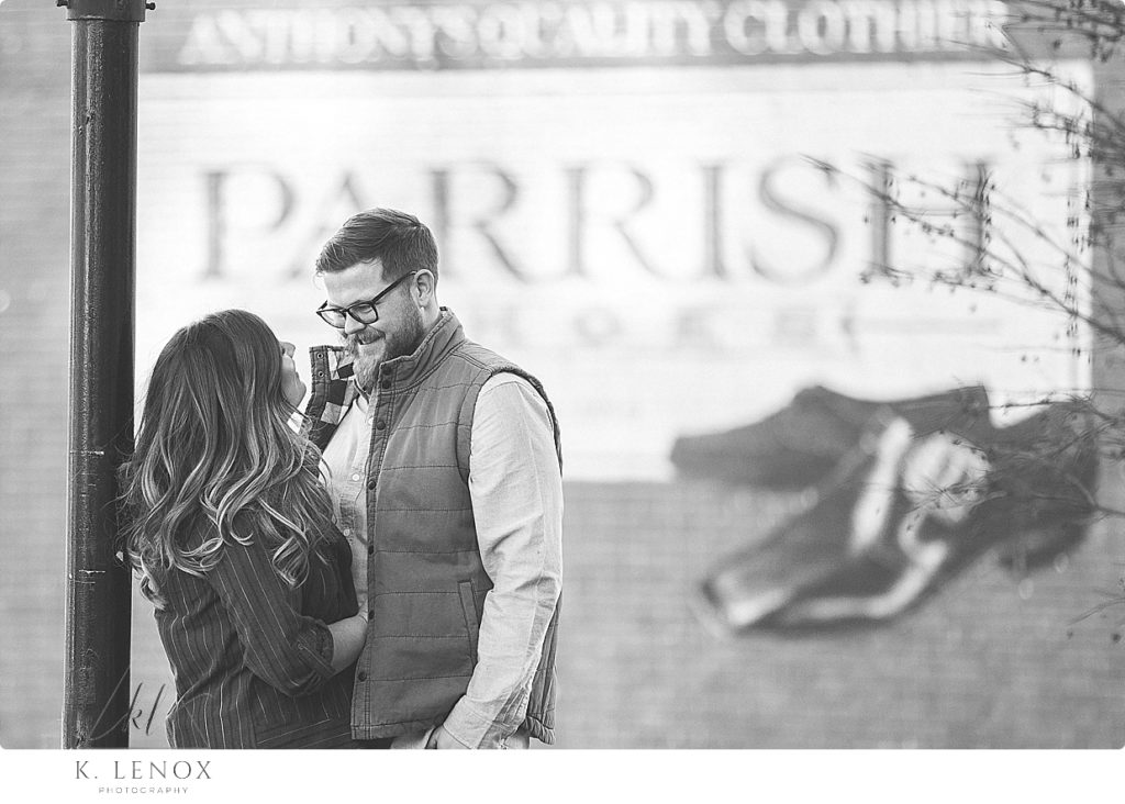 Black and White candid photo of a man and woman in front of the Parrish Shoes Sign from the Movie Jumanji in Keene NH. 