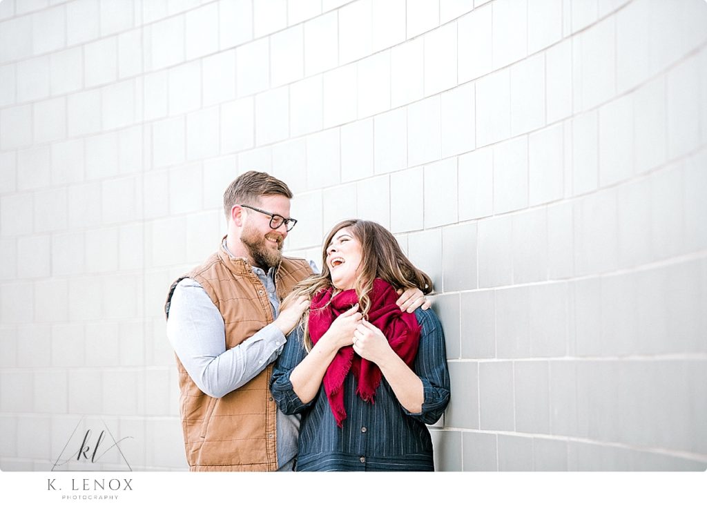 Light and Airy Winter engagement Photo of a man wearing a tan vest and a woman wearing a blue dress and a red scarf. 