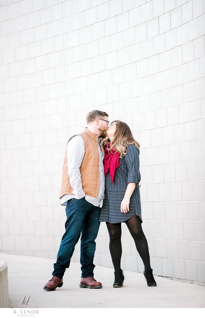 Light and Airy winter engagement photo of a man and woman in front of a white brick wall. 