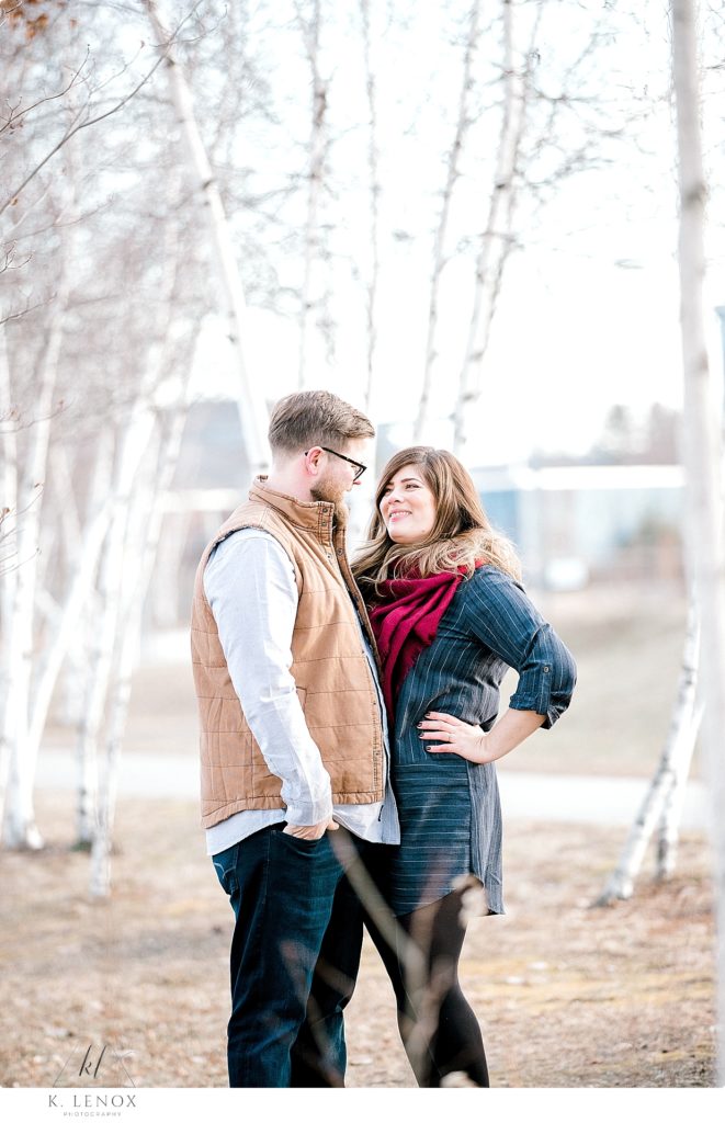 Light and Airy Winter Engagement photo of a man and woman surrounded by white birch trees. 