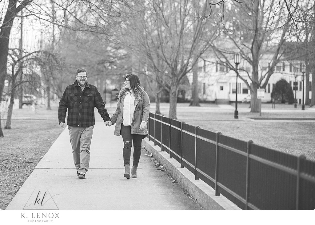 Black and White candid photo of a man and woman walking near Keene State College holding hands. 