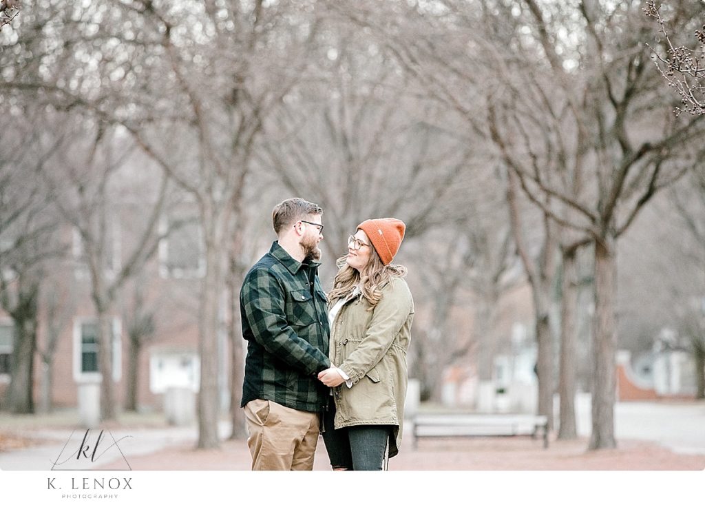Light and Airy Winter Engagement Session of a Man wearing a green plaid jacket and a woman wearing a coordinating jacket and orange winter hat. 