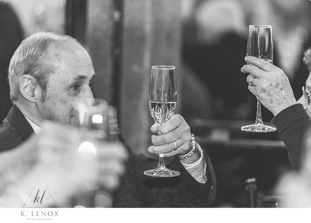 Black and white photo of champaign flutes being held up for a toast. 