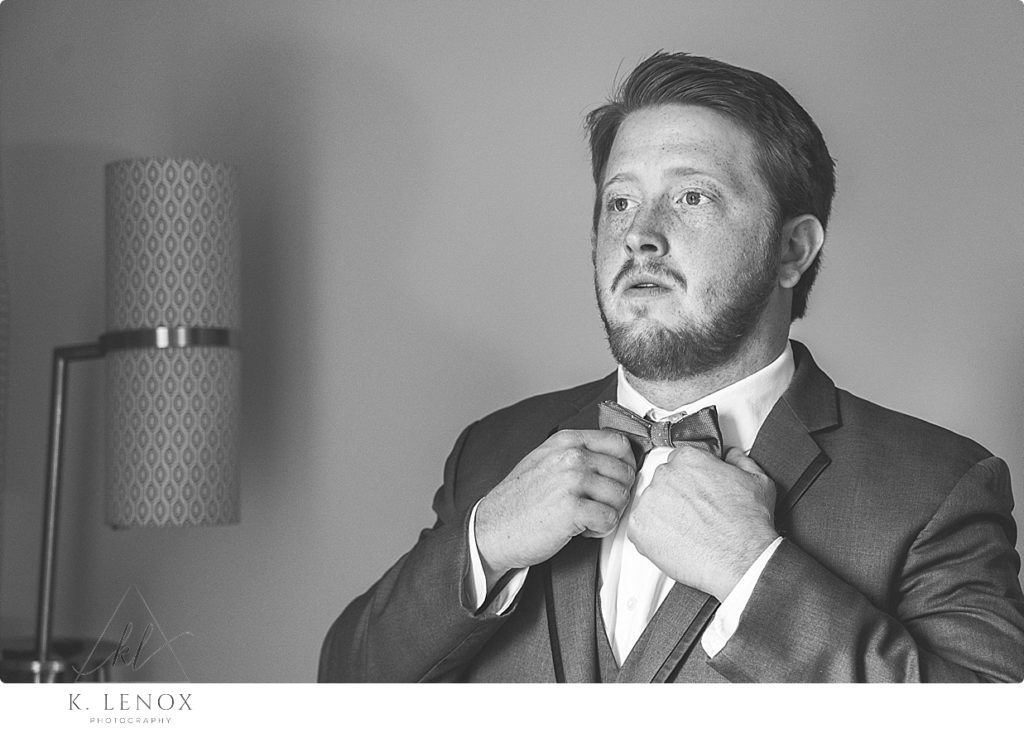 Black and White photo of Groom fixing his tie on his wedding day. 