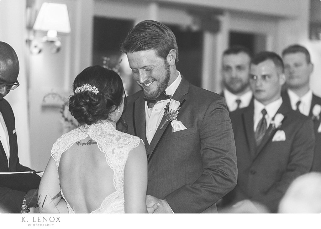 Black and White photo of a groom saying his vows and smiling. 
