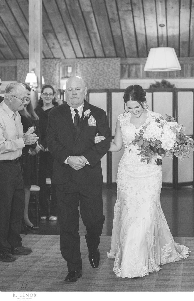 Black and White photo of a Dad walking his daughter the bride down the aisle for her indoor winter wedding at the Barn at Gibbet Hill. 