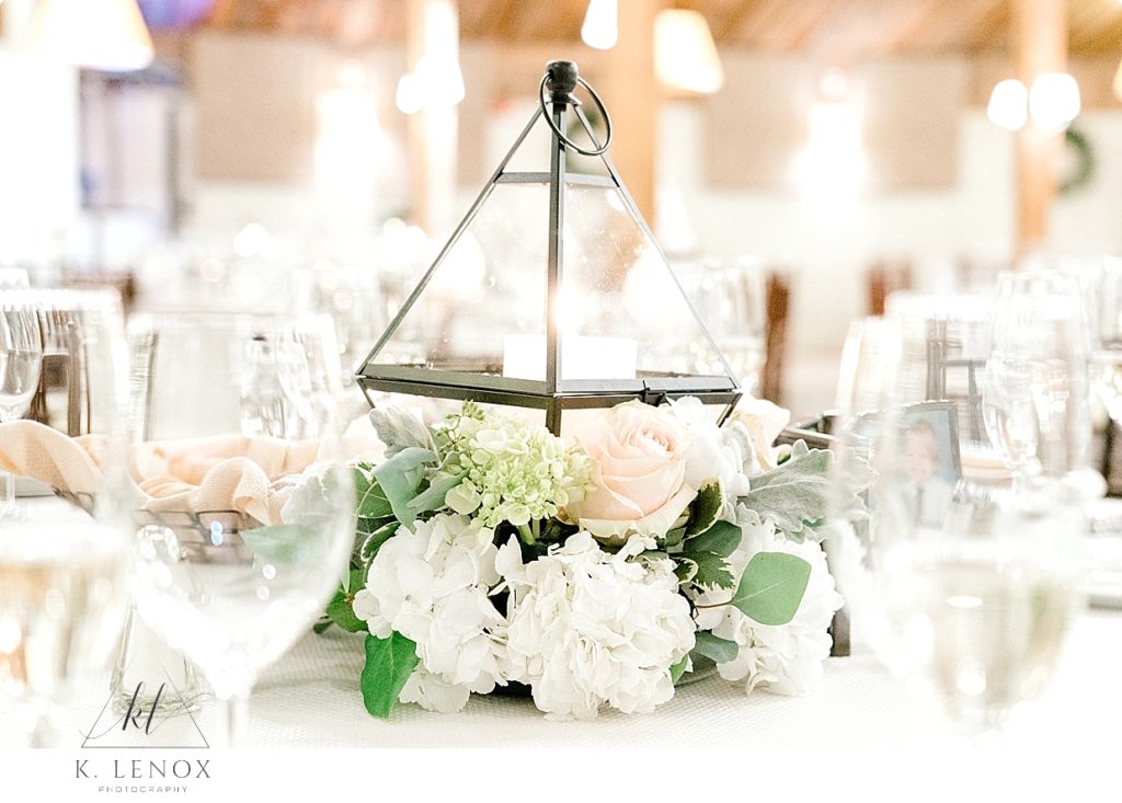 Triangular wedding table centerpiece with a white candle and light colored flowers. Winter Wedding the barn at gibbett hill. 