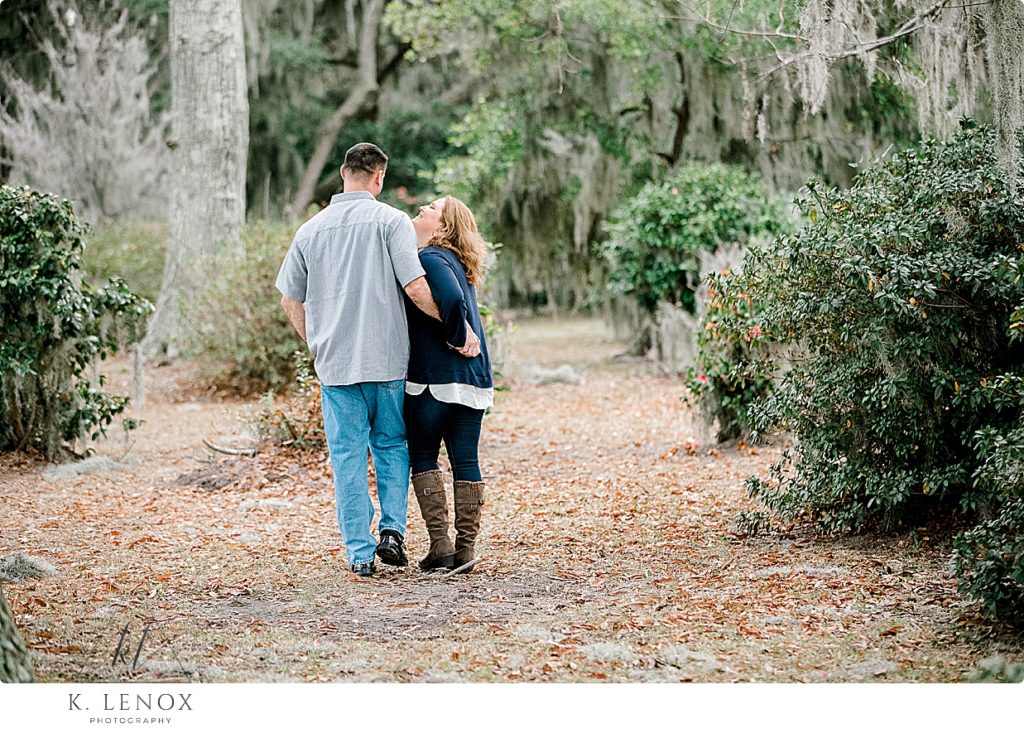 Couple walking away from the camera while laughing and holding hands during their Beaufort SC Engagement Session at Kate Gleason Park. 