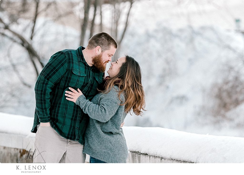 Woman wearing gray sweater and her fiance wearing a green plaid shirt interact during their winter engagement Session 