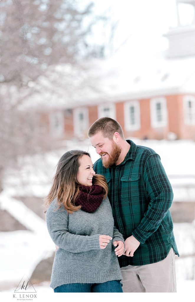 Candid photo of a man and woman laughing during their winter engagement session in Peterborough NH