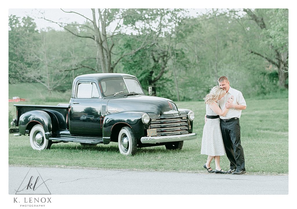 Light and Airy photo of a engaged couple in front of a black 1952 Chevy Truck during their photo session with K. Lenox Photography