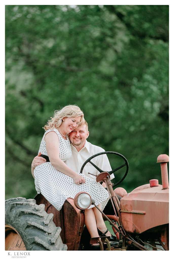 Man and Woman sit on an antique tractor for an engagement session photo