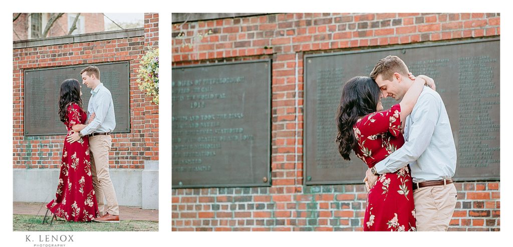 Woman wearing a red floral dress gets photo taken with her fiance during their Engagement Session in Peterborough NH.   Light and airy photography.  K. Lenox Photography