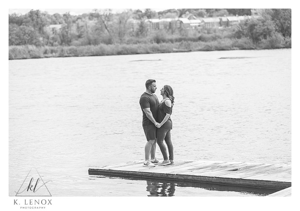 Black and White photo of a man and woman holding hands while standing on a dock next to a River in Brattleboro VT. 