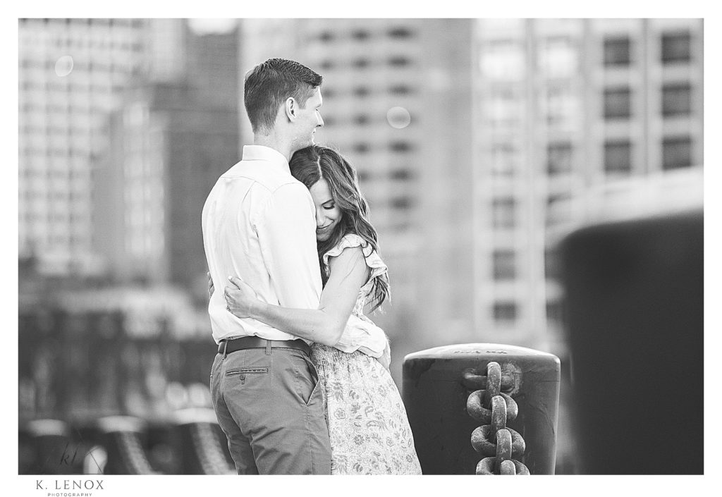 Black and White Photo taken during an engagement session in Boston.  Man and Woman hugging. 