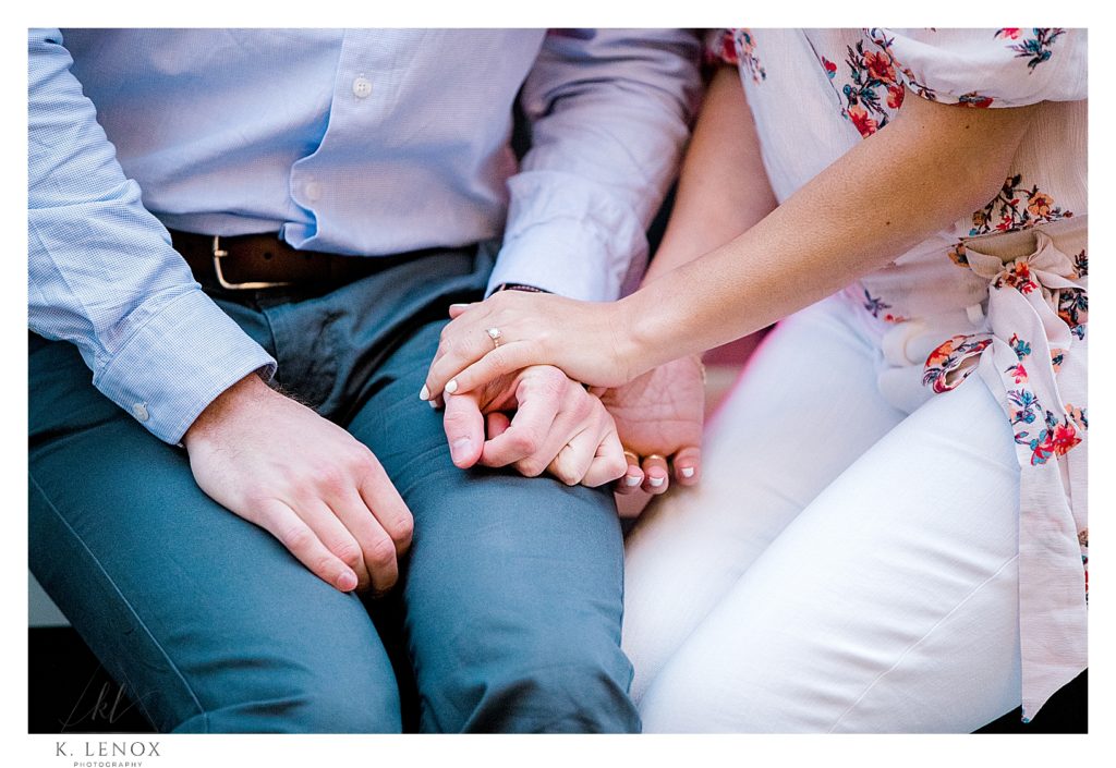 A detail photo of a man and woman holding hands showing her engagement ring. 