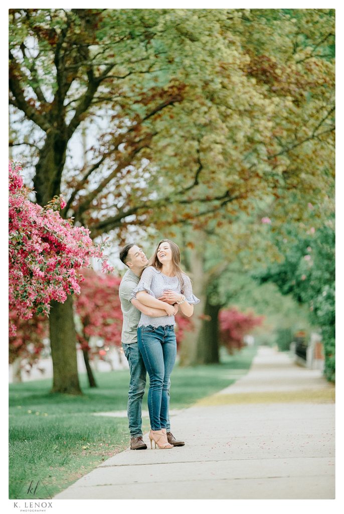 Man Hugs Woman from Behind during their Casual and Laid-back Spring engagement session in Keene. 