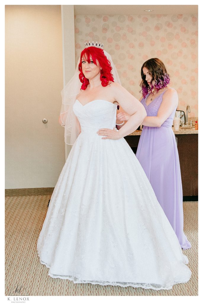 Enchanted Forest Wedding with a Game of Thrones Twist- Bride gets into her wedding gown as a Bridesmaid wearing a purple gown helps her tie the corset back. 