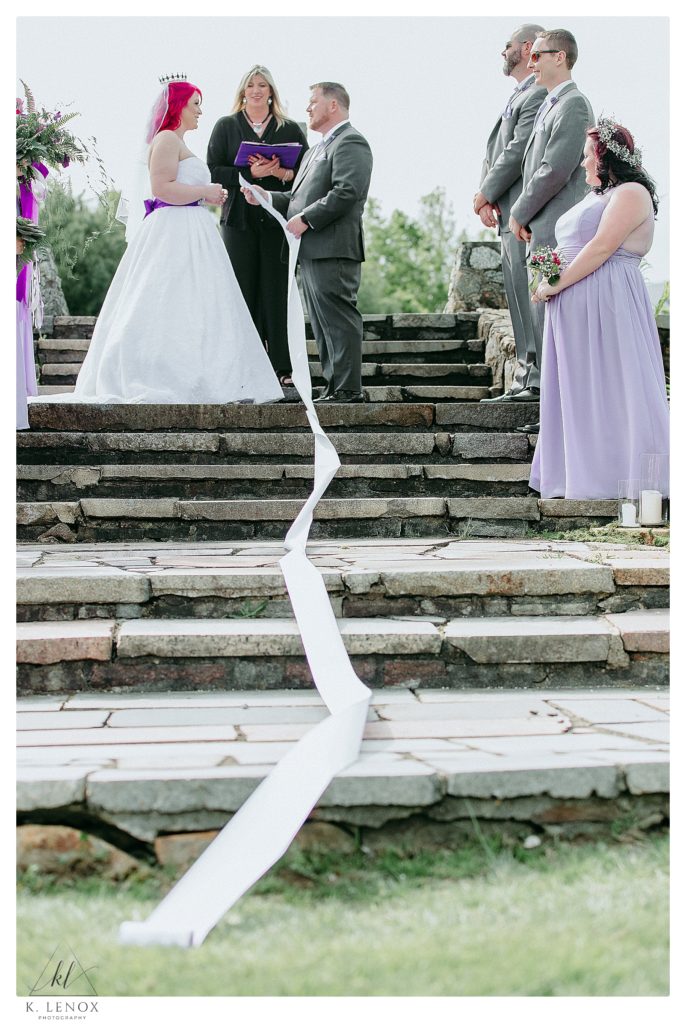 Groom has a long list of vows- on a scroll of paper for his Enchanted Forest Themed Wedding at the stone terrace at the Shattuck Golf Course in Jaffrey NH. 
