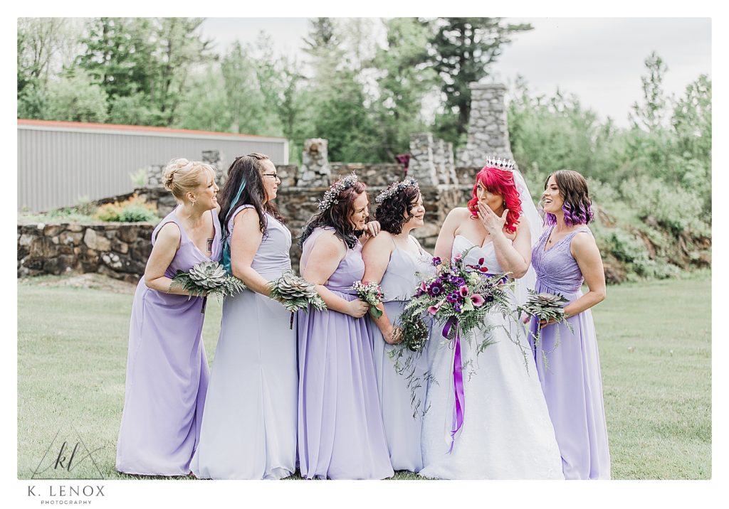 Bridesmaids wearing purple pose with the bride in front of a stone terrace for a Game of Thrones Themed Wedding. 