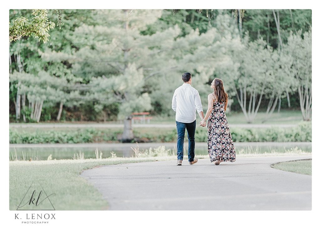 Photo of a couple walking holding hands in Benson Park NH during their engagement session with K. Lenox Photography. 