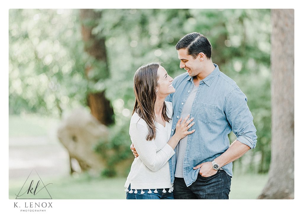 Candid photos from a Light and Airy Engagement Session in Benson Park NH.  A couple  looking at each other wearing jeans and white shirts. 
